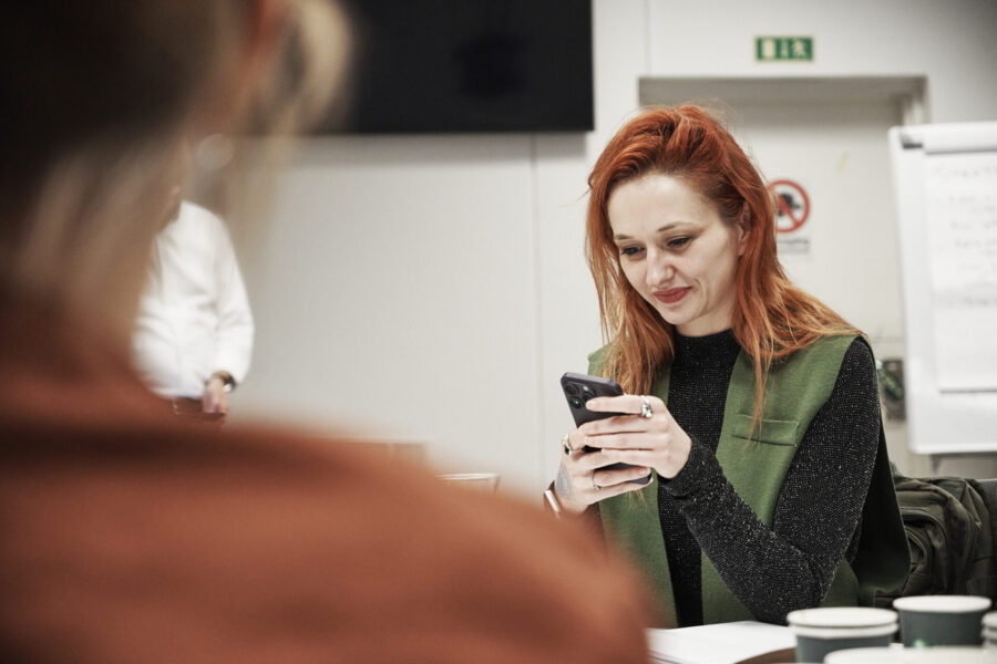 Kvinna i klassrum tittar på mobiltelefon